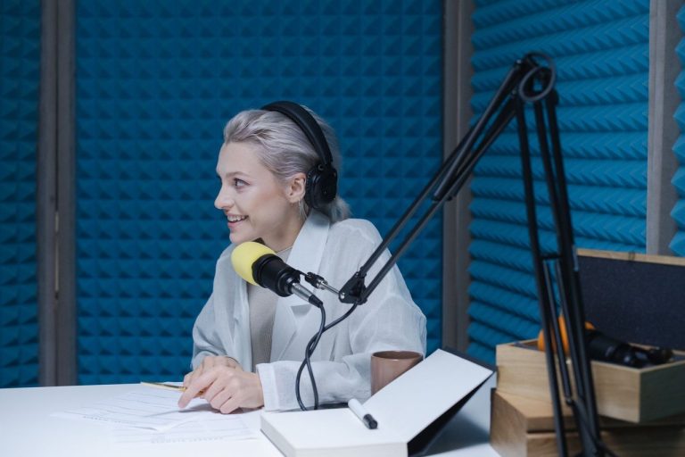 Spotify levará programa de parceria a podcasters brasileiros em outubro Mulher usando fones de ouvido e falando ao microfone durante a gravação de um podcast em um estúdio.