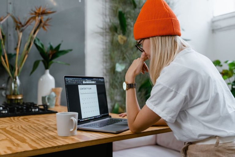 Mynd amplia uso de IA em campanhas com micro e nanoinfluenciadores Criadora de conteúdo trabalha em um plano diante de um laptop em um escritório doméstico.